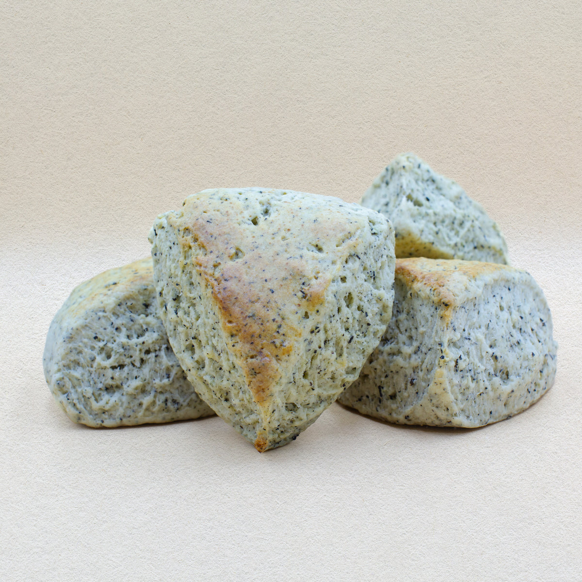 Four delicious English scones infused with Earl Grey tea. Specks of real tea are visible throughout the fluffy triangular scones. 