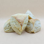 Four traditional triangular English classic scones with a golden brown crust and a delightfully craggy and fluffy center - perfect from cream and jam.