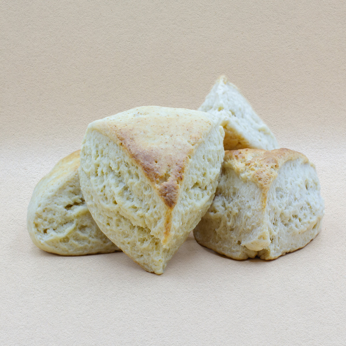 Four traditional triangular English classic scones with a golden brown crust and a delightfully craggy and fluffy center - perfect from cream and jam.
