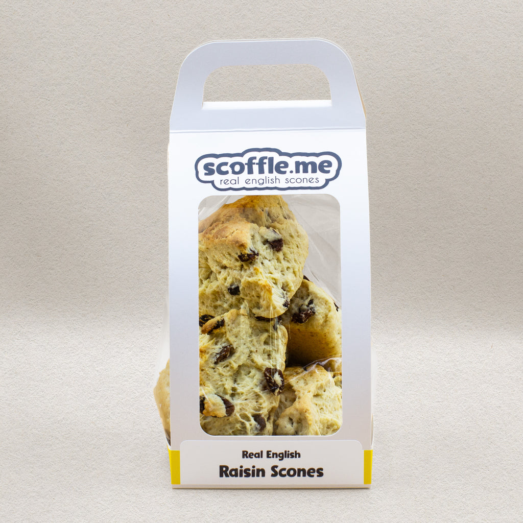 A cute white handled bag showcasing four delicious and rustic looking triangular raisin scones.