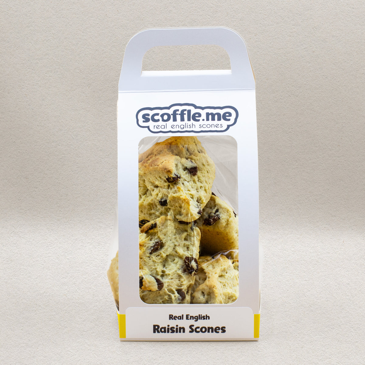 A cute white handled bag showcasing four delicious and rustic looking triangular raisin scones.