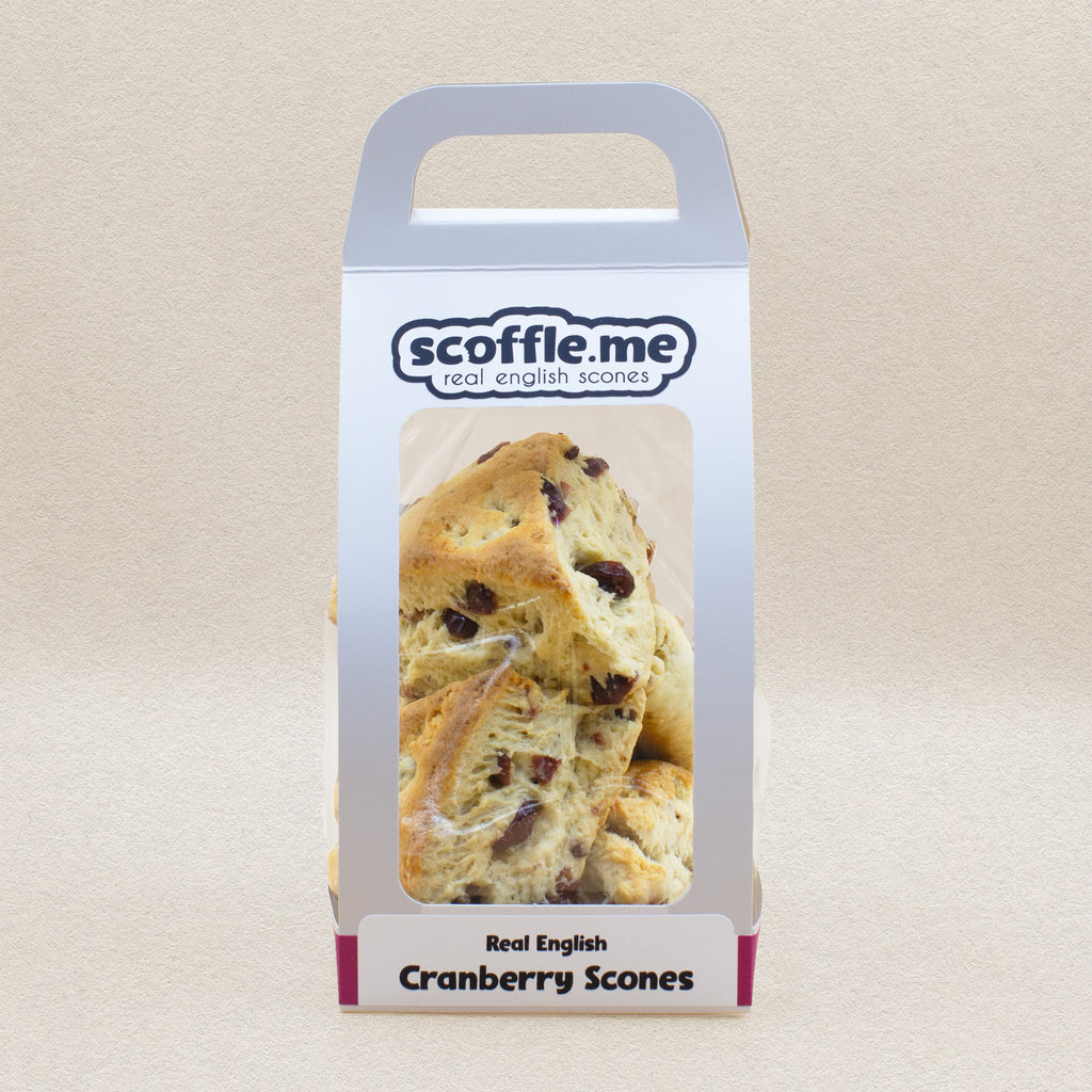 A cute white handled bag showcasing four delicious and rustic looking cranberry triangular scones.