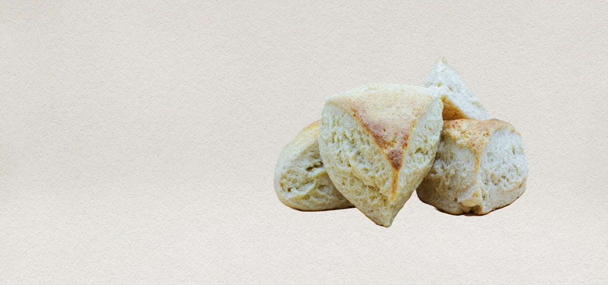 Four plain English scones crafted using traditional methods. Featuring a delightful golden brown crust and a white fluffy center. 